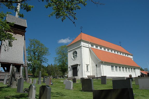 En vitmålad kyrka mot blå himmel, vid sidan av kyrkan finns ett klocktorn