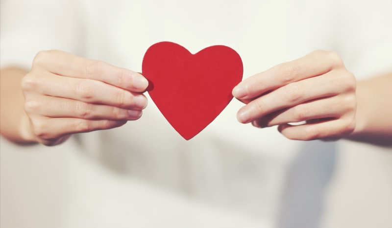 Ett par händer som håller i ett rött hjärta.