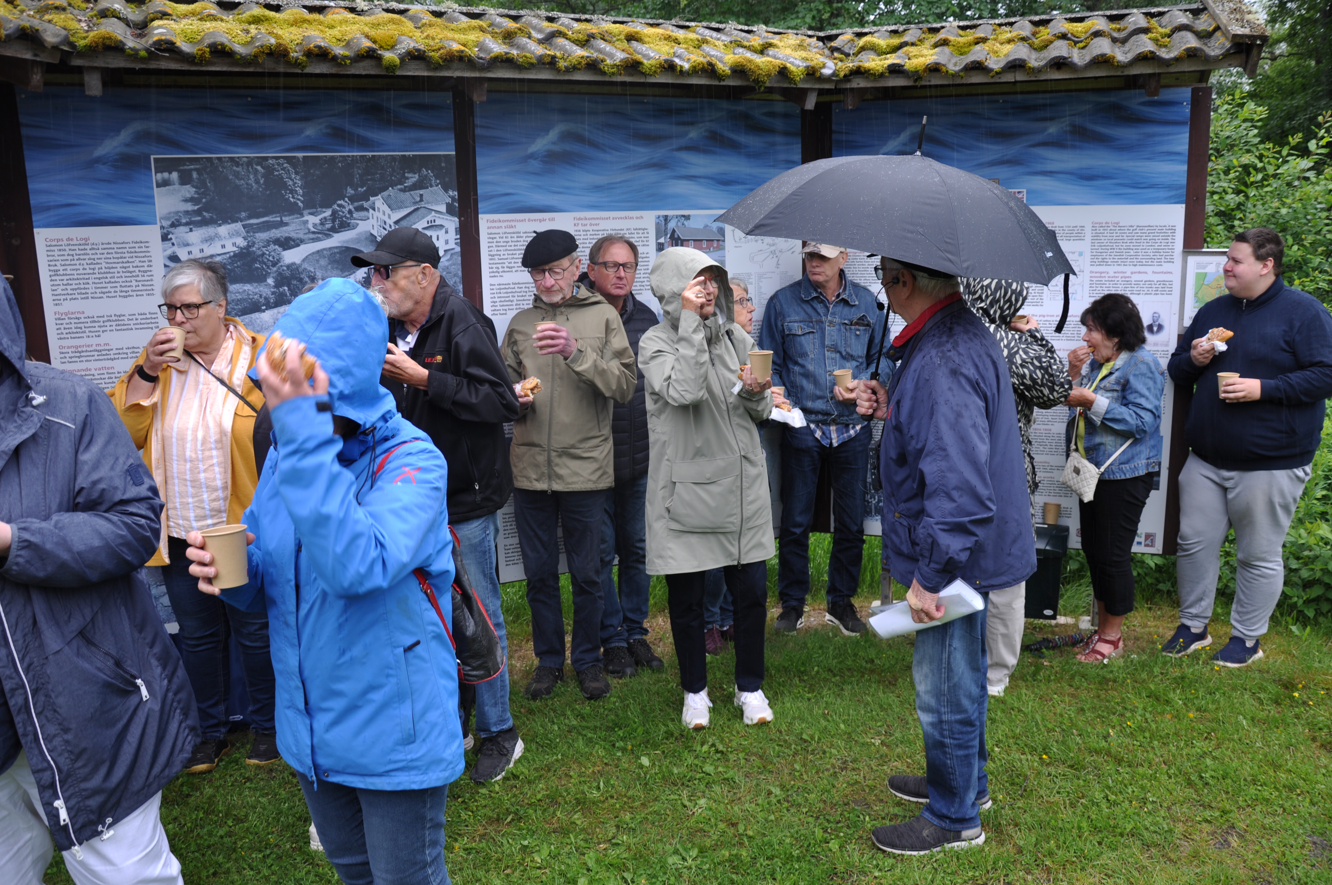 Deltagare med paraply och regnkläder i det dåliga vädret.