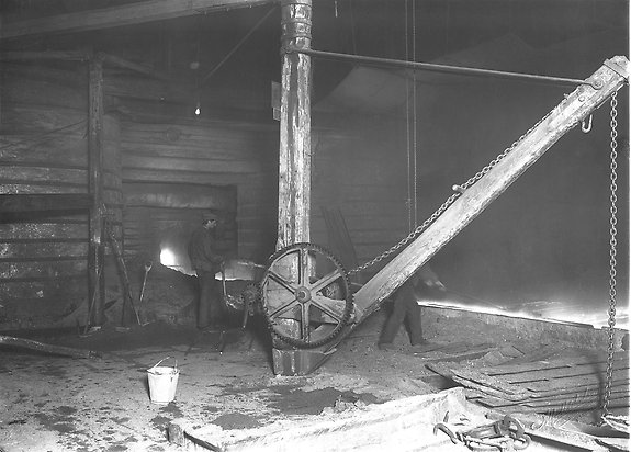 svartvitt foto på män som arbetar i ett järnbruk