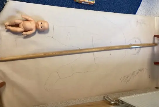 Foto på ett stort papper som ligger på golvet, man har ritat av ett barn på pappret i full storlek.