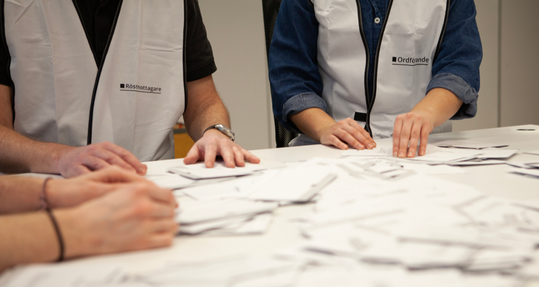 Tre röstmottagare som räknar röstkort.