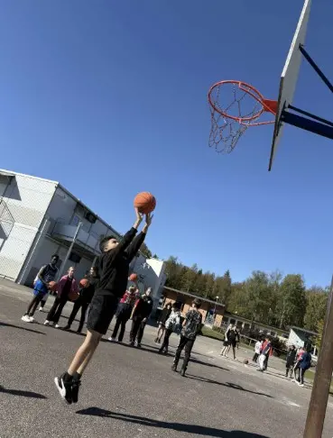 Foto på elever som hoppar och kastar en basketboll.