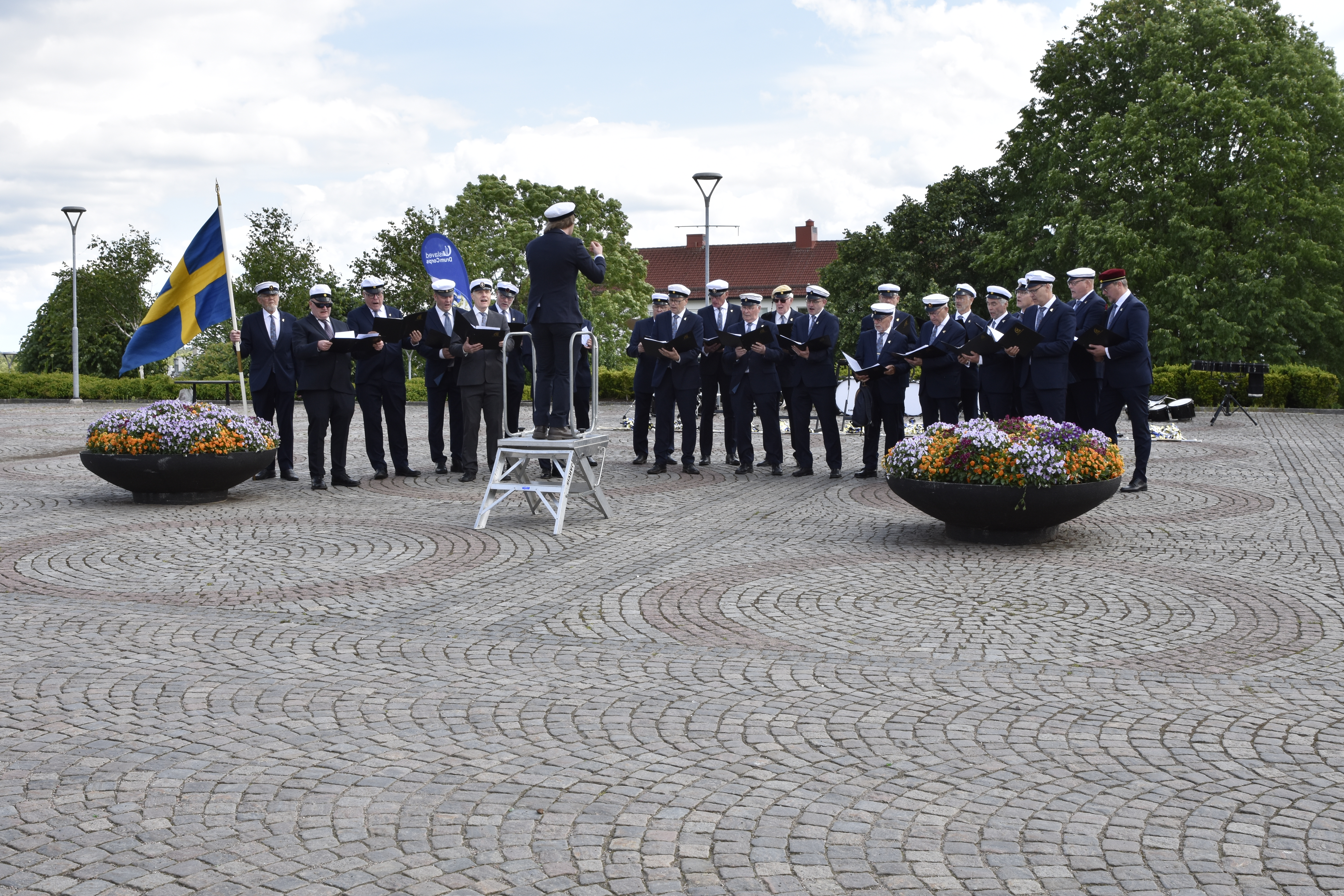 En manskör som sjunger på ett torg.
