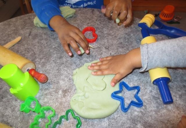 Barnhänder som leker med lera