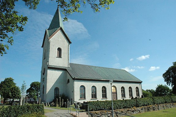 en vit kyrka med ett spetsigt torn och valvade fönster. 