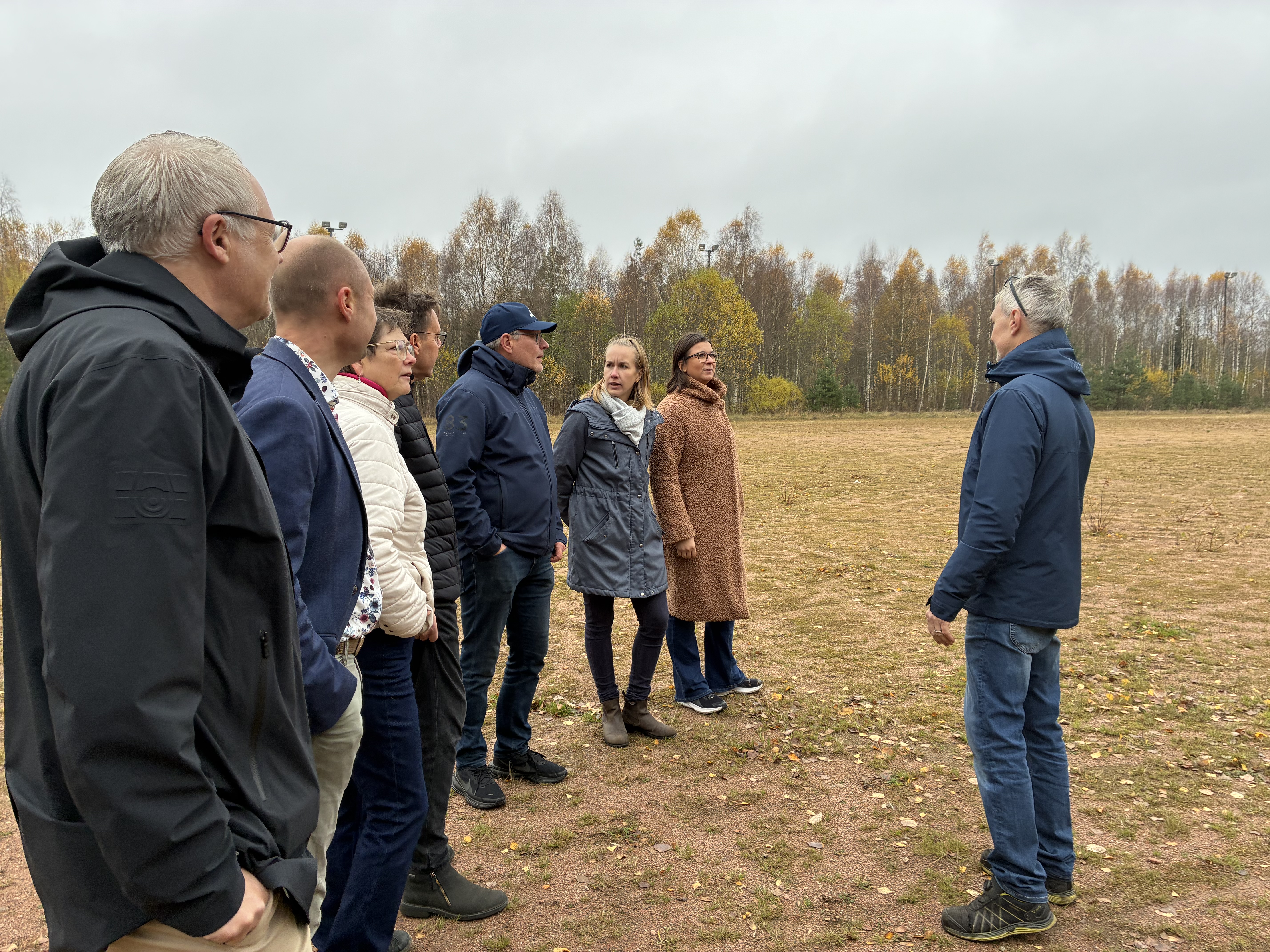 En grupp människor tittar ut över den gamla grusplanen