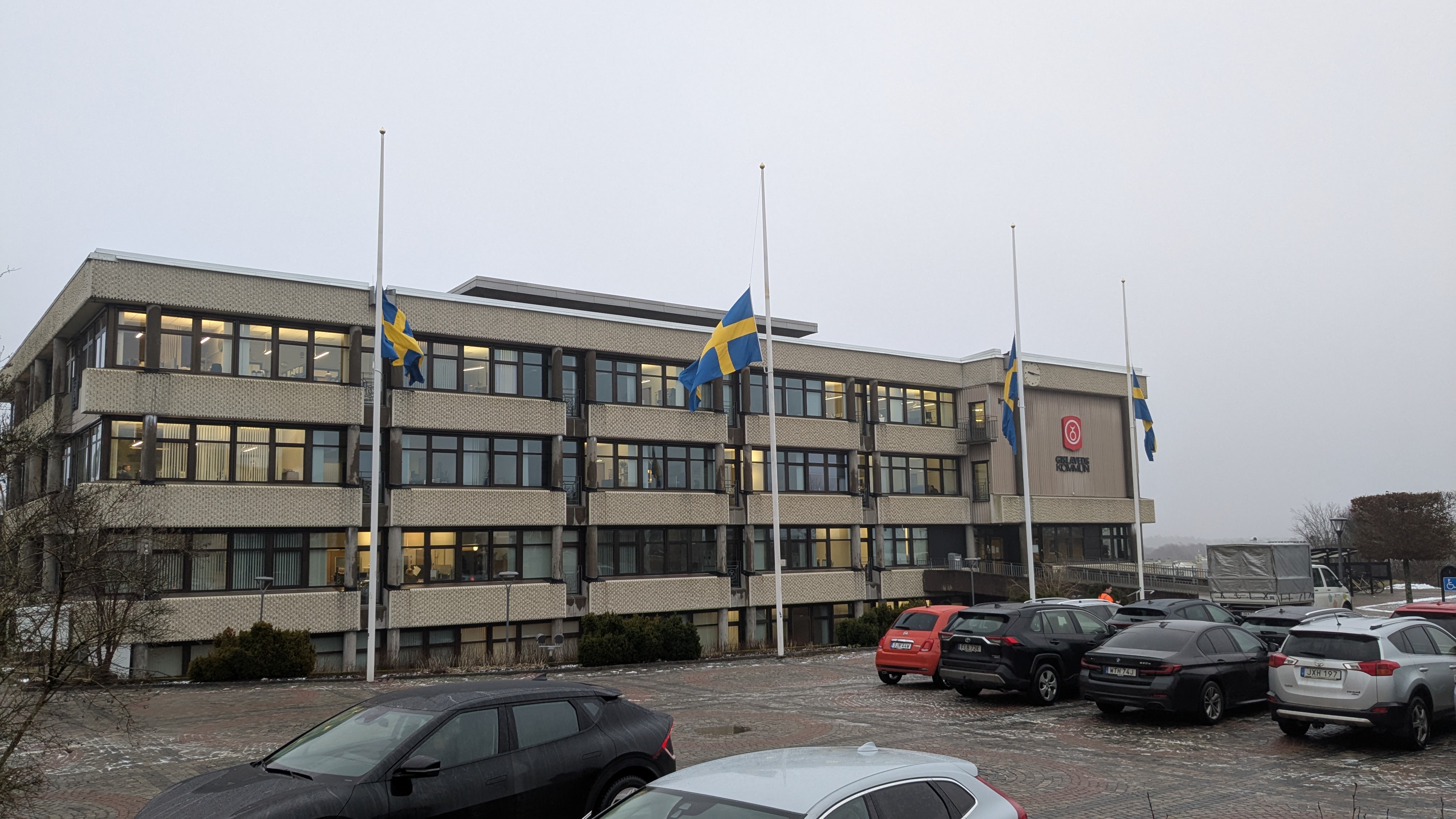 exteriör bild på kommunhuset. svenska flaggan vajar på halv stång.