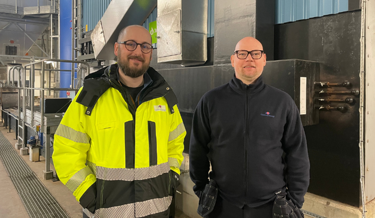 Två män i en industribyggnad. I bakgrunden syns maskiner.