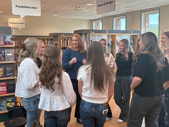 Foto där man ser hur Annie Lööf samtalar med flera ungodmar på biblioteket.
