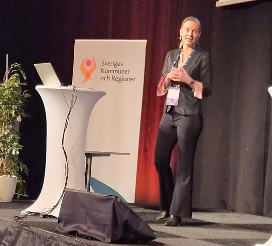 Närbild på Alma Maslan när hon står på scen och håller föredrag