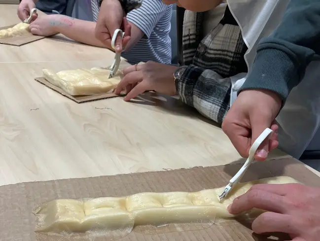 Närbild på händer som håller i en sax och får prova på att klippa tråd.