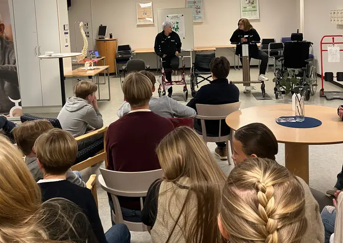 Gruppbild på elever som sitter och lyssnar på personal som berättar om yrken inom vård och omsorg