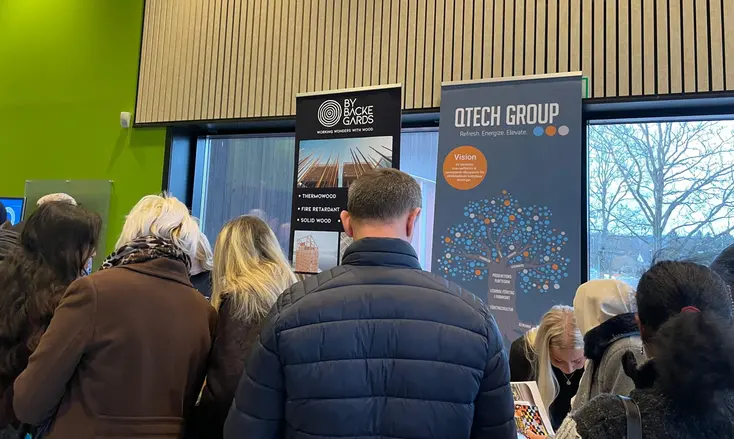 Flera personer står med ryggen mot kameran. I bakgrunden syns rollups och ett folkvimmel.