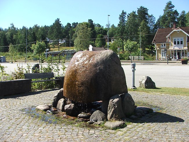 en stor sten med vatten som rinner ur den på ett torg
