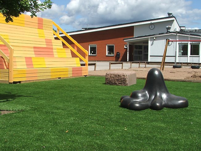 Skulptur av en glänsande blobb som står på en skolgård