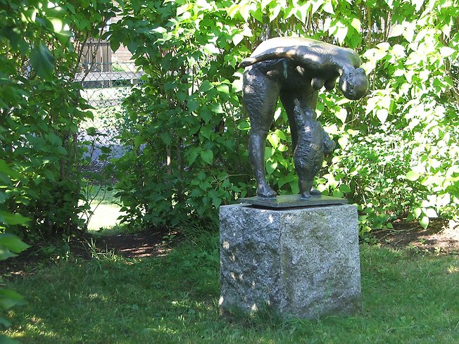Skulptur i sten av en kvinna som står framåtlutad