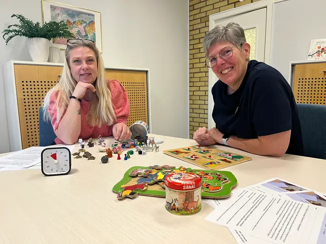 Foto på två kvinnor vid ett bord, på bordet ligger leksaker och andra förskolesaker.