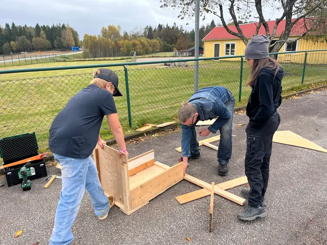 Foto på elever som håller i en lådbil och en förälder som hjälper till och snickrar.