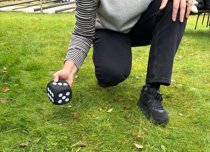 Foto på en hand som håller i en stor tärning.