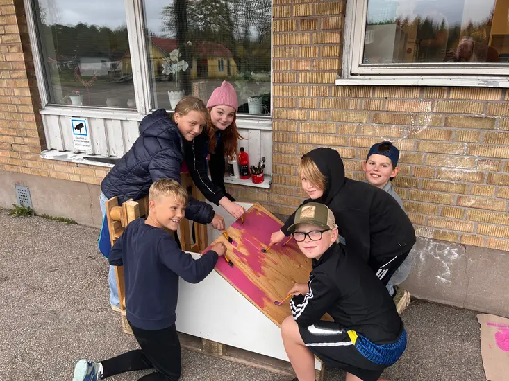 Elever som står tillsammans och bygger på en lådbil.