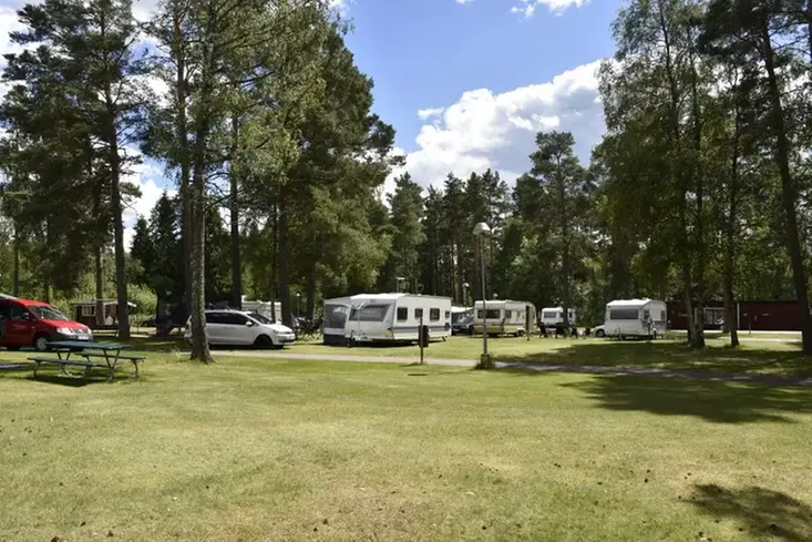 Bild på campingen under sommartid, gräsyta, träd och husvagnar 