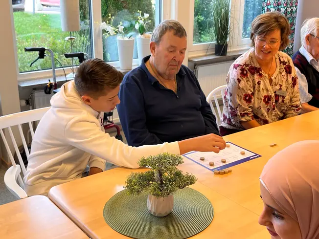 Foto på en elev som hjälper en äldre man.