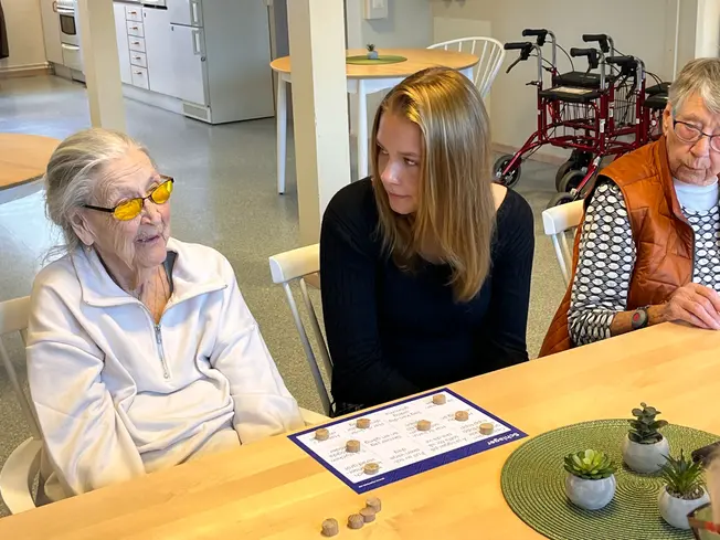 Foto på en elev som lyssnar på en äldre dam.