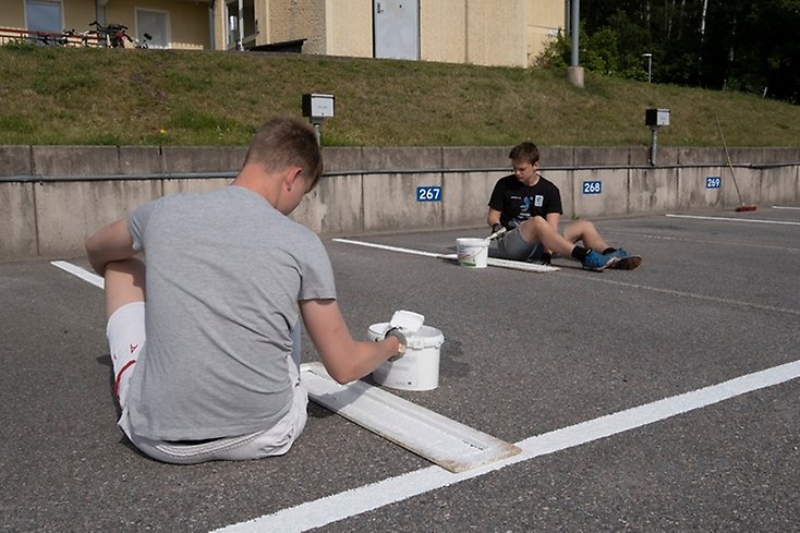 Ungdomar som målar parkeringslinjer