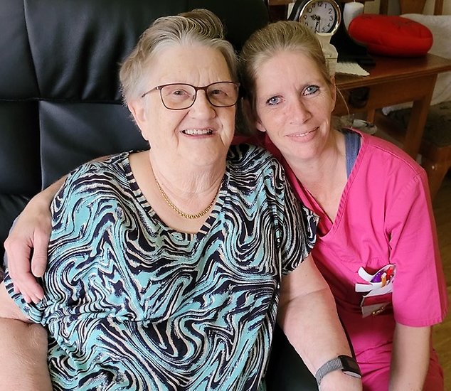 En undersköterska håller om en äldre kvinna.