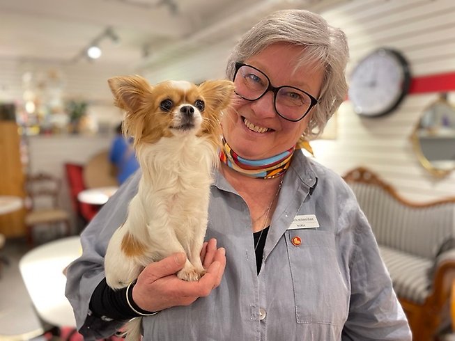 En kvinna och en hund med café i bakgrunden.