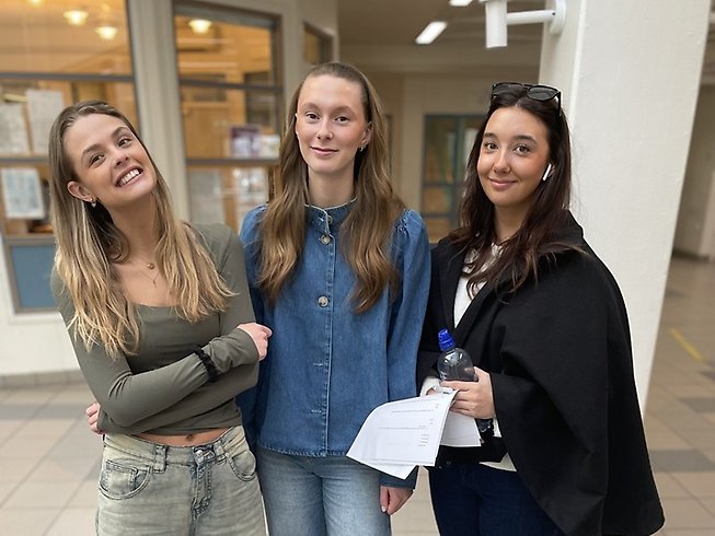 Tre unga tjejer står utanför gymnasiets expedition