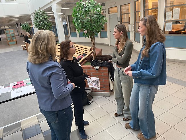 Två unga tjejer och två politiker samtalar.