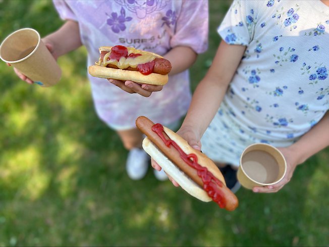 Ett foto på två barn som håller i varsin korv med bröd.