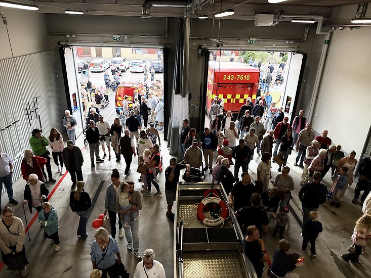 Helikoptervy över brandstationen invändigt. Massvis av nyfikna invånare går i lokalerna.