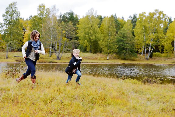 En mamma och ett barn som springer utmed en sjö.