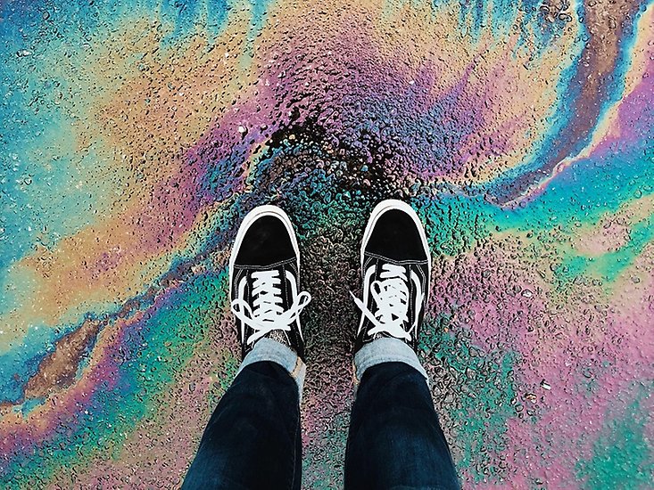 Ett benpar med svarta skor som står på en regnbågsfärgad mark.