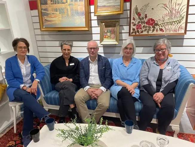 Fem personer sitter tillsammans vid en soffa.